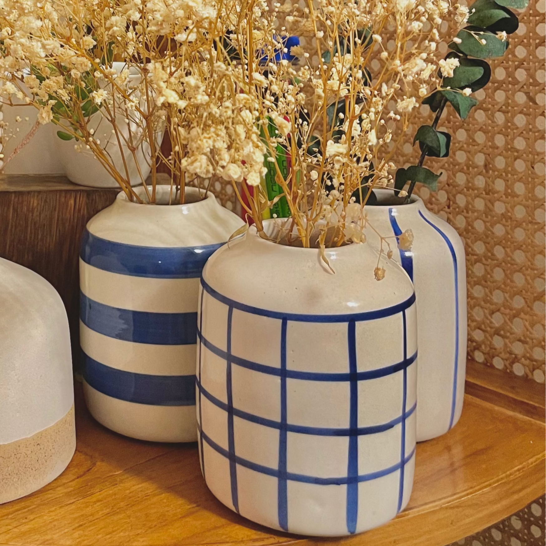 Decorative arrangement ofBlue Tinea Trio  vases with dried plants on a wooden shelf.