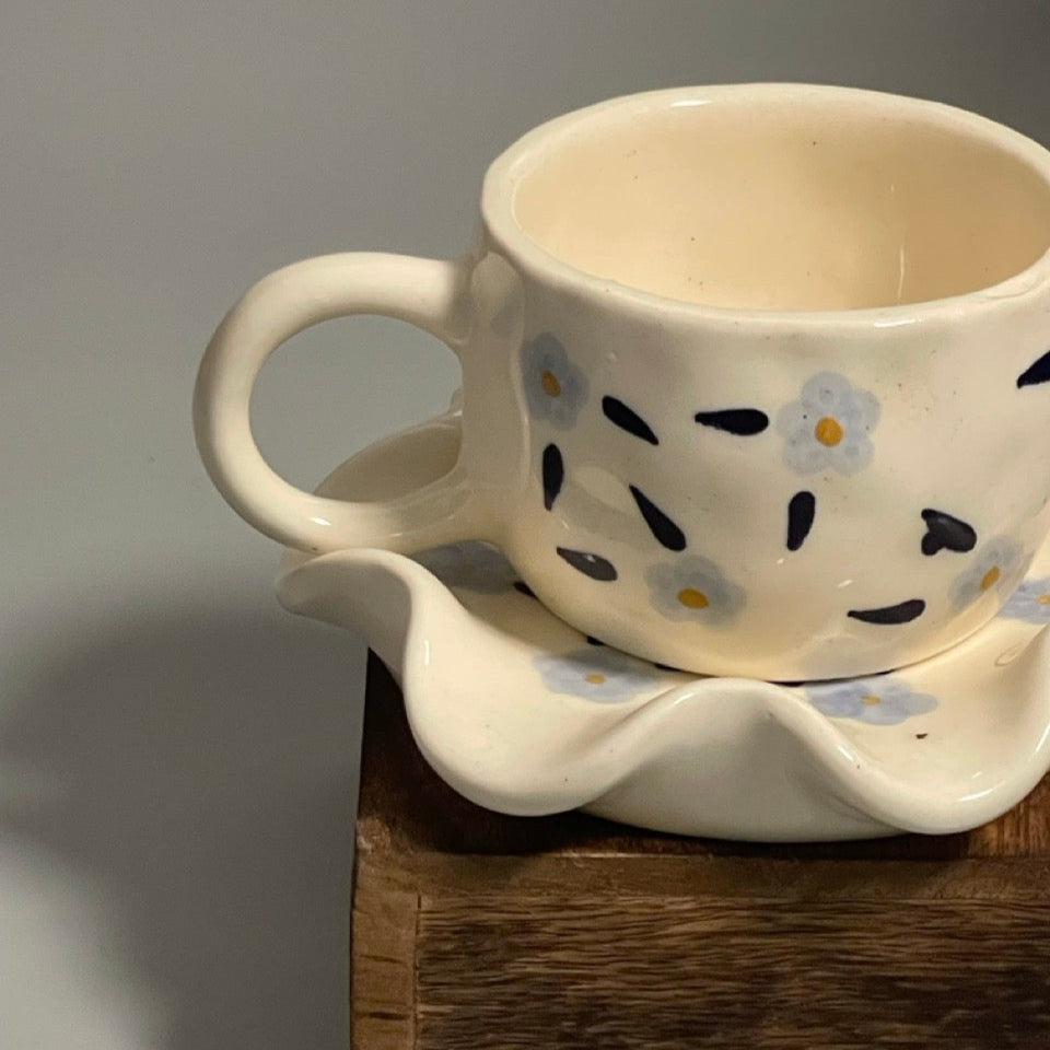 Floral ceramic cup with purple flower motifs and flower-shaped saucer