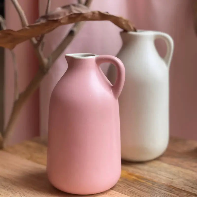 Pink and white Jugscapes ceramic jugs on a wooden surface with a pink background