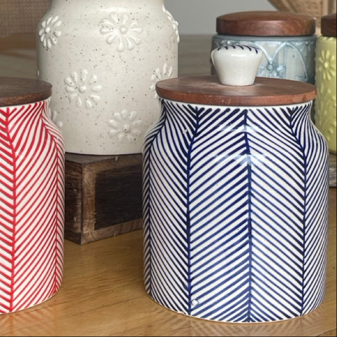Decorative canisters with patterned lids on a wooden surface.