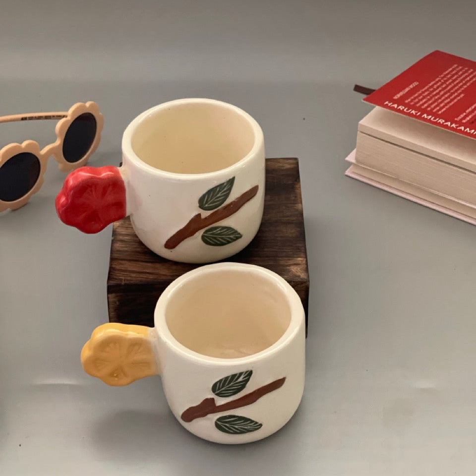 Set of 2 ceramic cups with birdtail-shaped handles and branch motifs in yellow and red