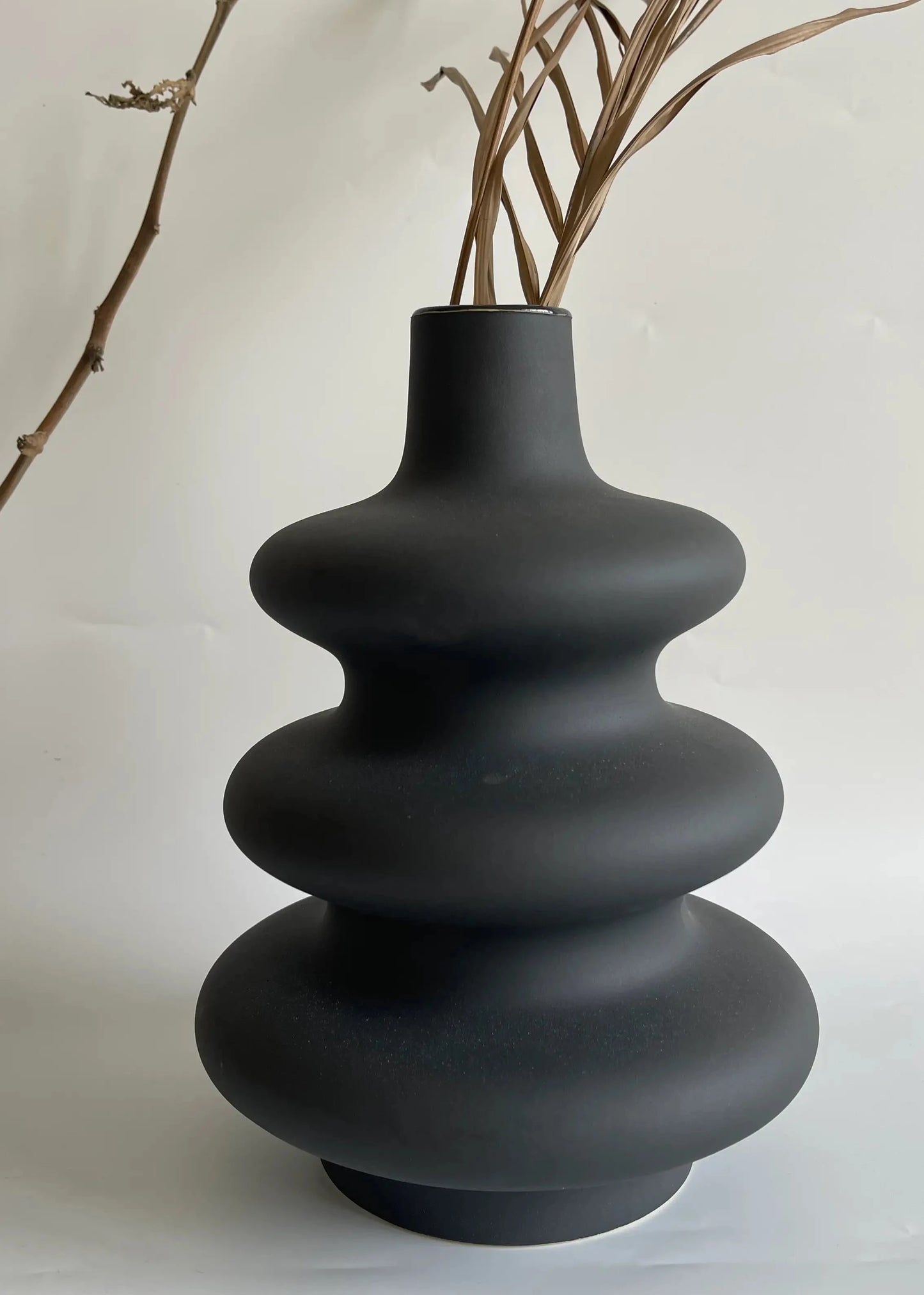 Black ceramic vase with a textured, layered design on a white background