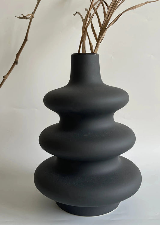 Black ceramic vase with a textured, layered design on a white background