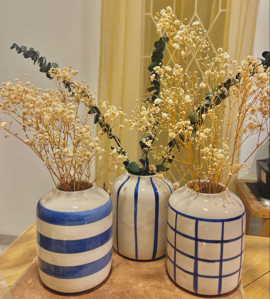 Three decorative vases with blue patterns on a table against a neutral background