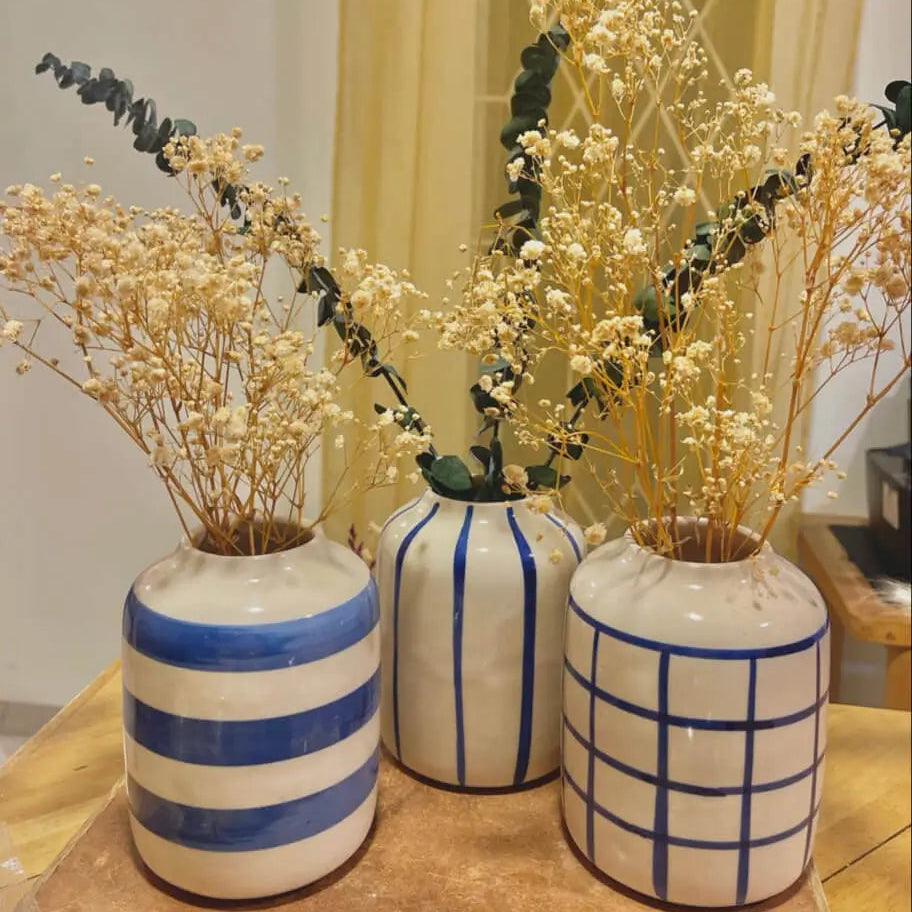 Set of Three Blue Lines Trio vases with striped and grid patterns containing dried plants on a wooden surface