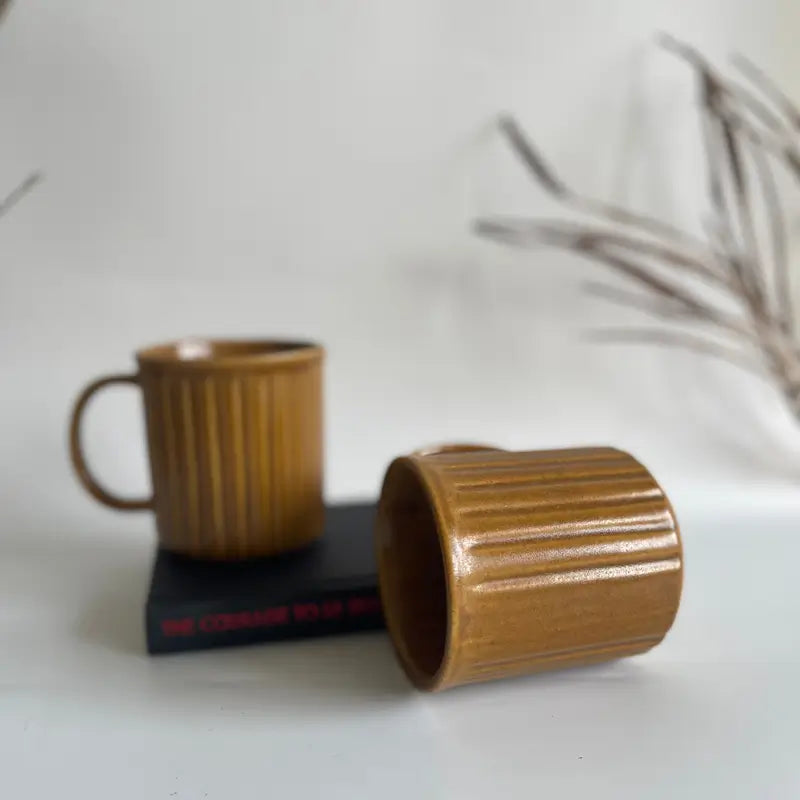 Two brown Everyday Ribbed mugs on a white surface with a blurred background