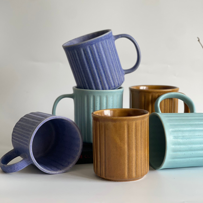 Ceramic ribbed mugs available in pastel purple, pastel blue, and earthy brown