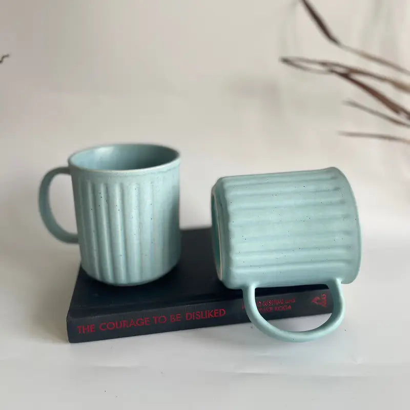 Two Everyday Ribbed mugs light blue mugs on a book with a minimal background