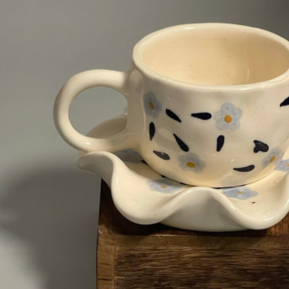 Floral ceramic cup with purple flower motifs and flower-shaped saucer