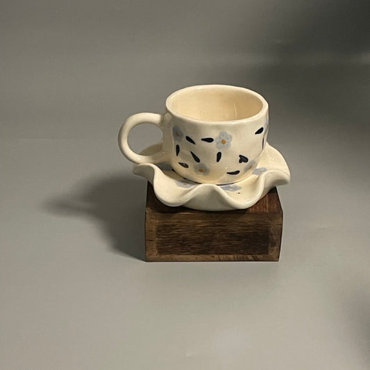 Floral ceramic cup with purple flower motifs and flower-shaped saucer