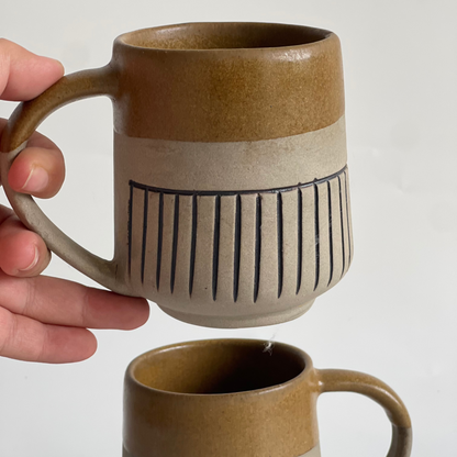 Rustic ceramic mug with glyph design and half brown glaze finish