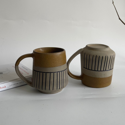 Rustic ceramic mug with glyph design and half brown glaze finish