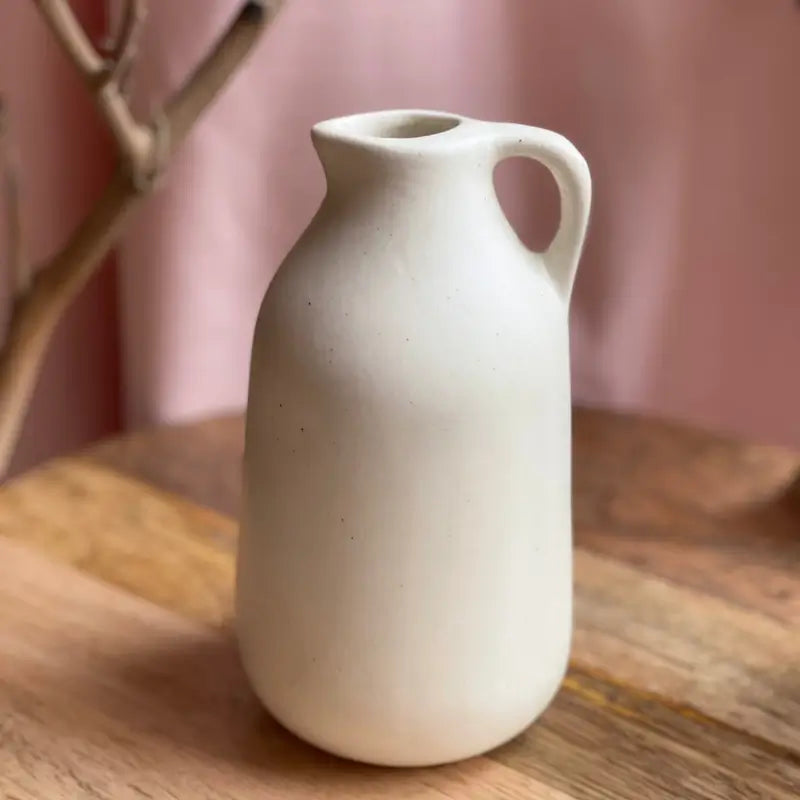 White ceramic Jugscapes vase on a wooden surface with a pink background
