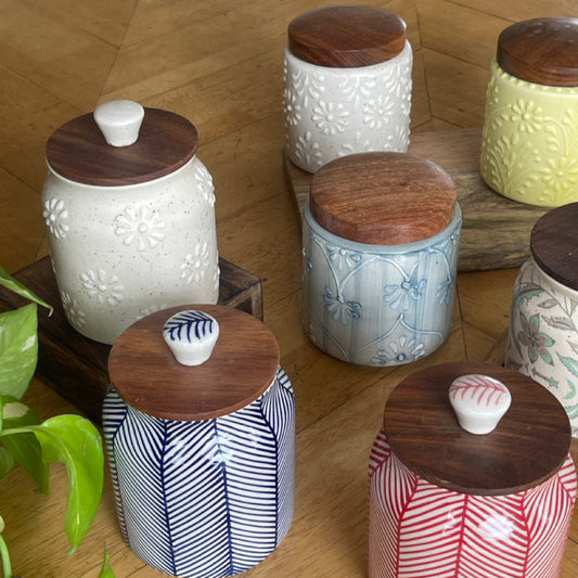 Set of ceramic jars with wooden lids on a wooden floor