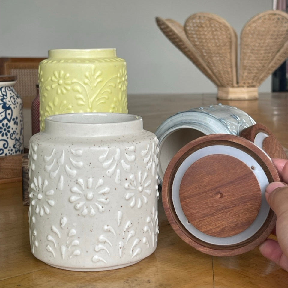Three ceramic jars with different designs on a wooden surface