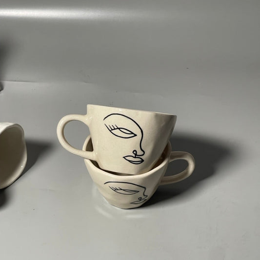 Minimal ceramic mug with single-line face outline in neutral matte finish