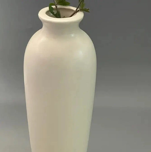 White Ivora ceramic vase with a plant on a gray background closeup