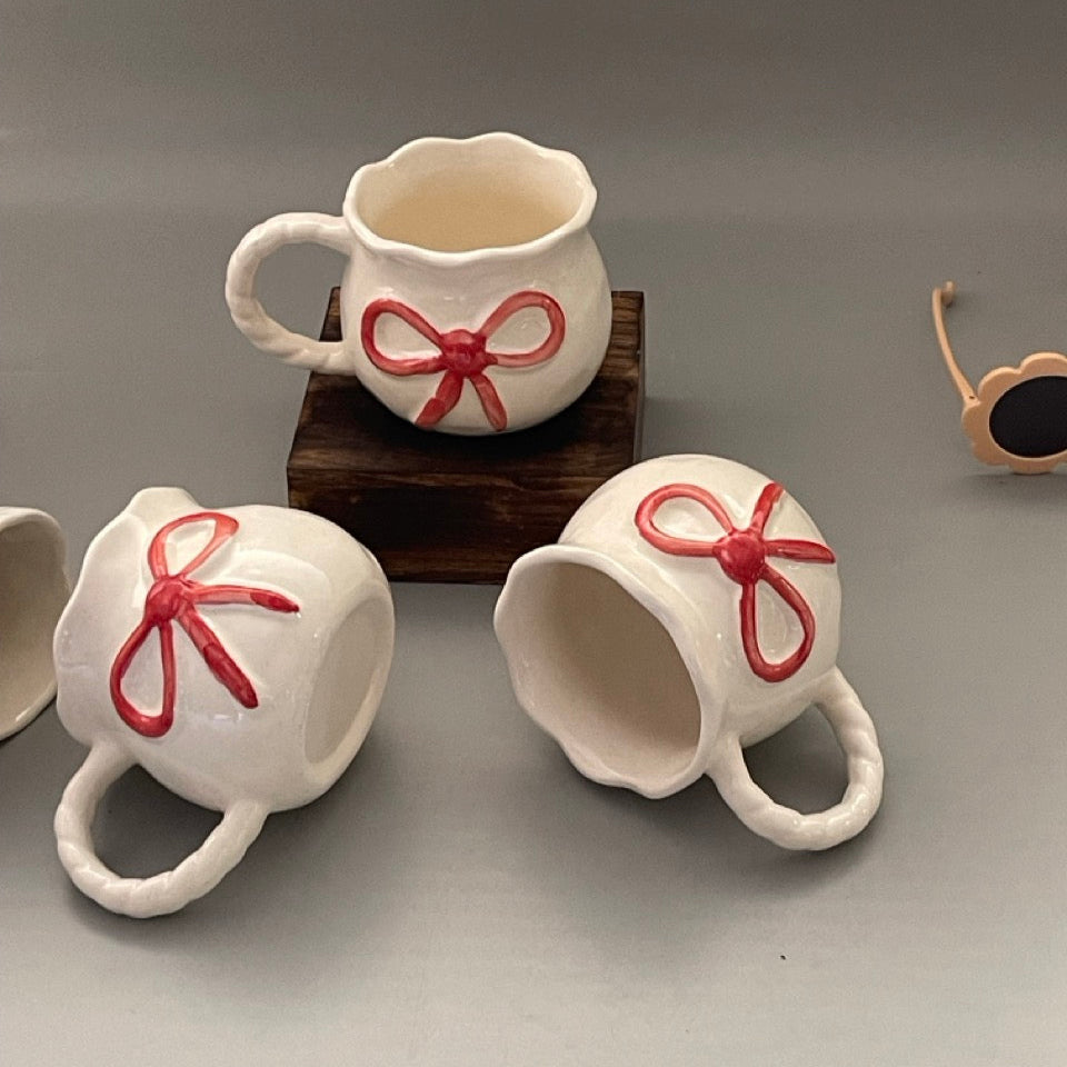 Glossy ceramic mug with bow front and sculpted handle, Pinterest-inspired design in pastel tones