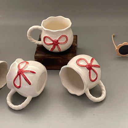 Glossy ceramic mug with bow front and sculpted handle, Pinterest-inspired design in pastel tones