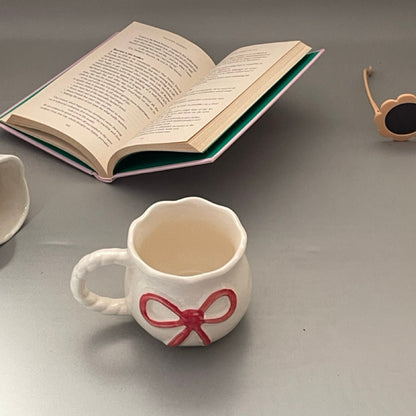 Glossy ceramic mug with bow front and sculpted handle, Pinterest-inspired design in pastel tones
