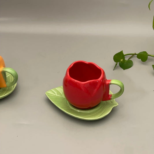 Ceramic cup shaped like a lotus with matching leaf-shaped saucer in glossy red, yellow, and green variants