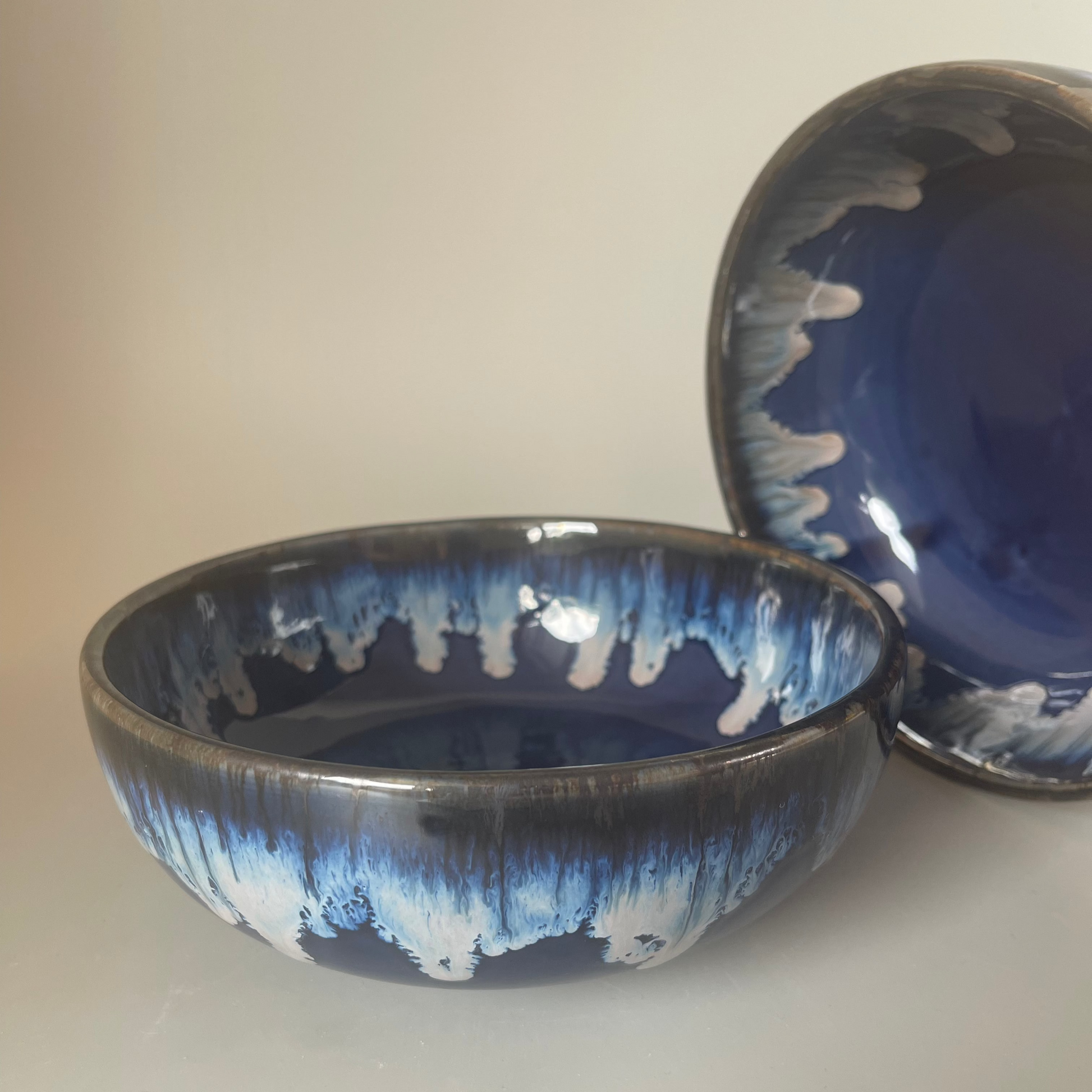 7 inch ceramic Seasque serve bowl with blue interior and white dripping glaze exterior, inspired by ocean waves