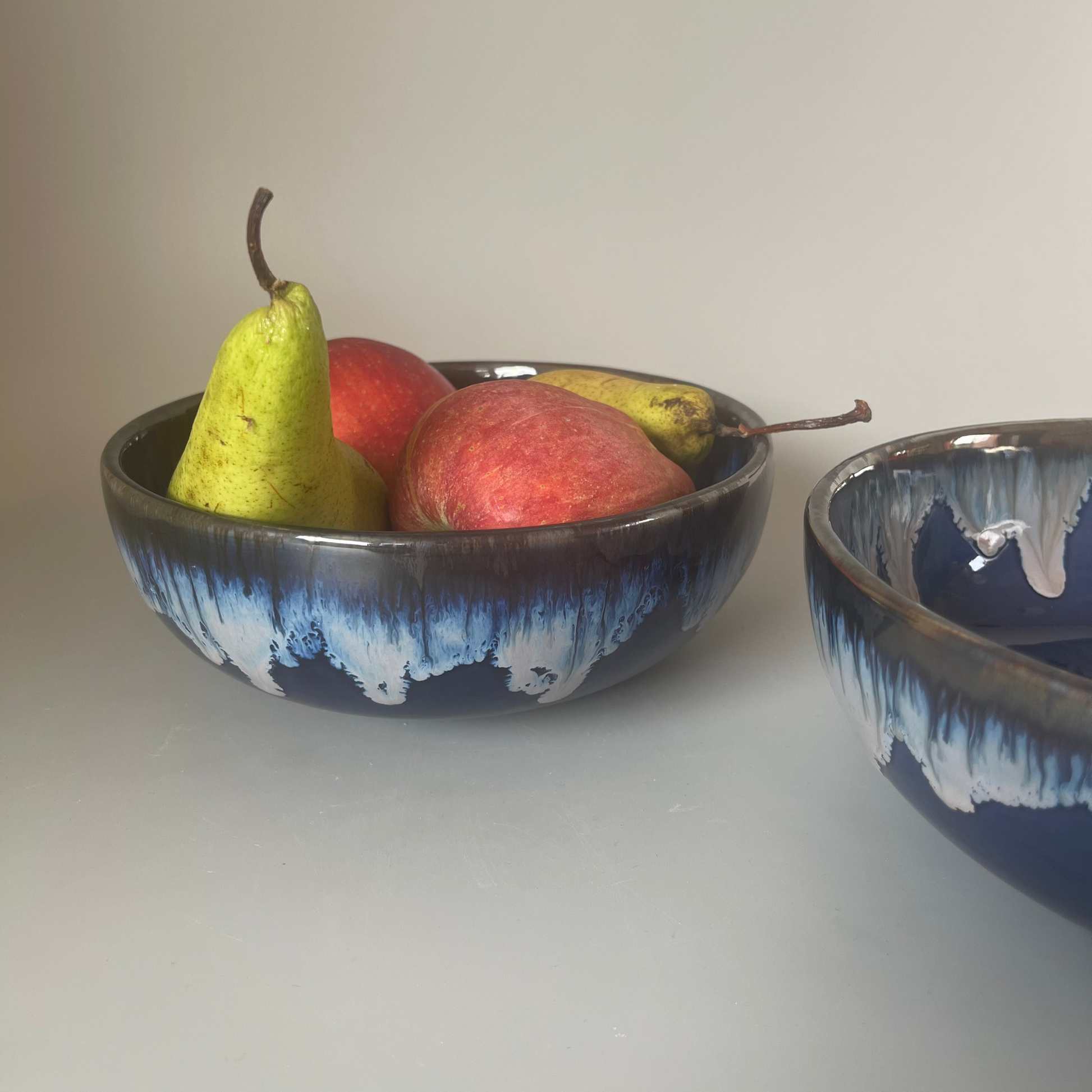 7 inch ceramic Seasque serve bowl with blue interior and white dripping glaze exterior, inspired by ocean waves