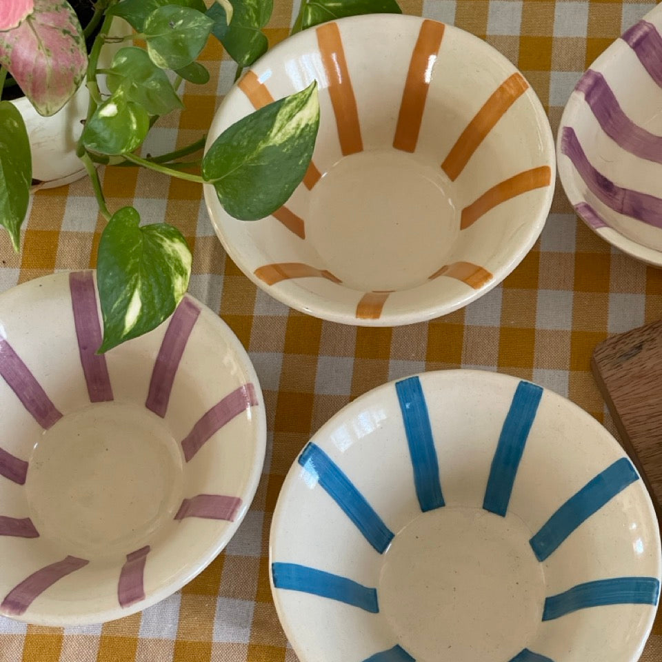 Three ceramic bowls with striped patterns on a checkered tablecloth.