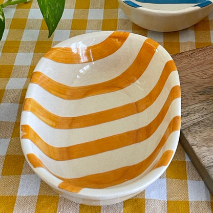 Two ceramic bowls with striped patterns on a checkered tablecloth.