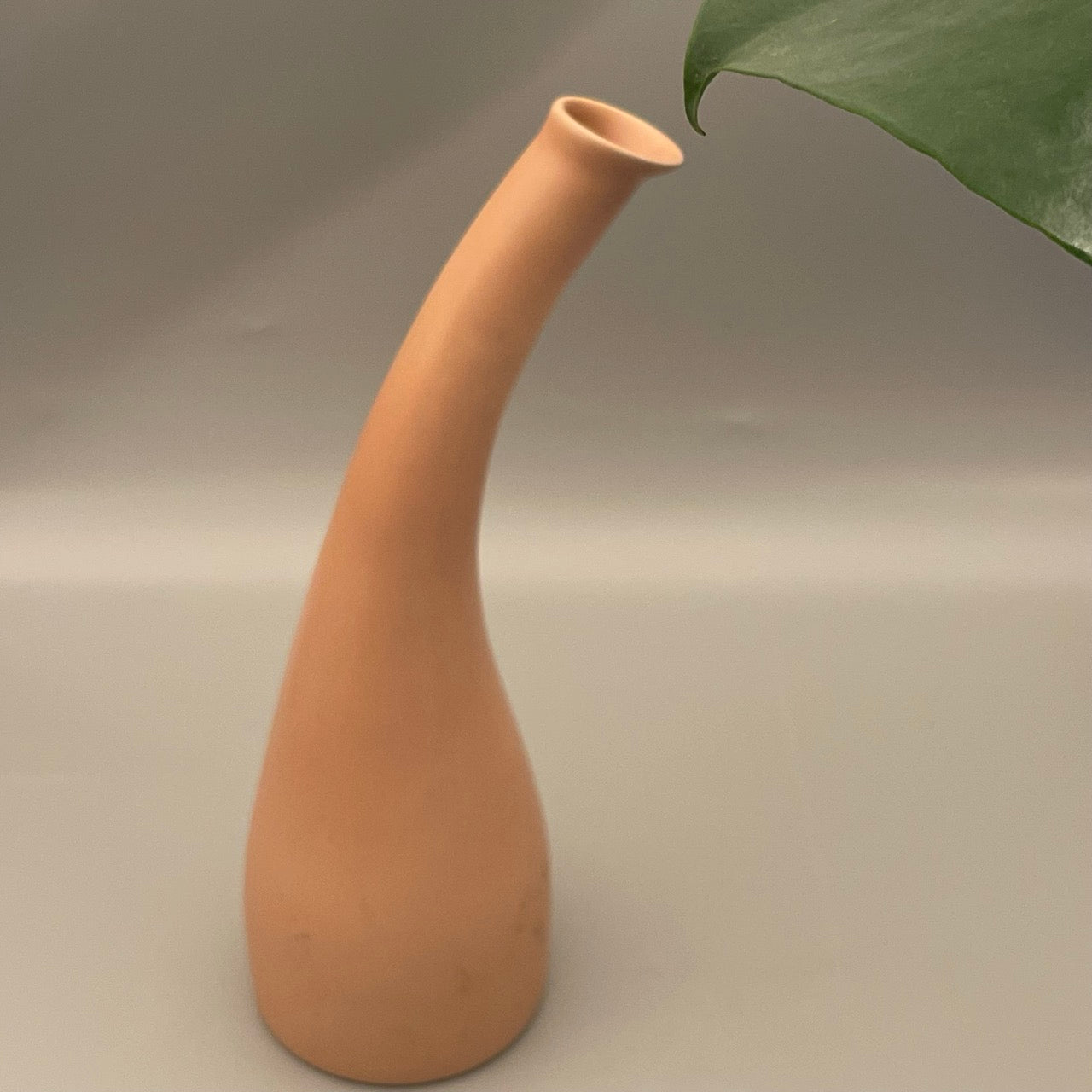 Tall ceramic vase with narrow neck and wide base in solid color finish