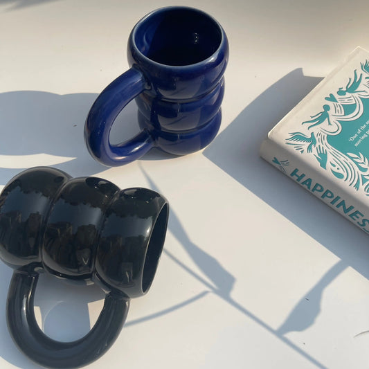 Twilight Duo Mugs on a white surface with a book titled 'Happiness' in the background.