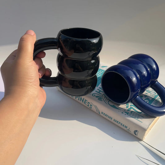 Twilight Duo Mugs on a book with a hand holding one of the black mugs.