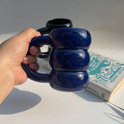 Hand holding a blue mug of the Twilight Duo Mugs with a book in the background