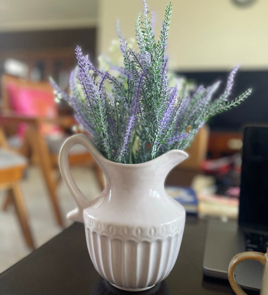 White pitcher with lavender-like plants on a table
