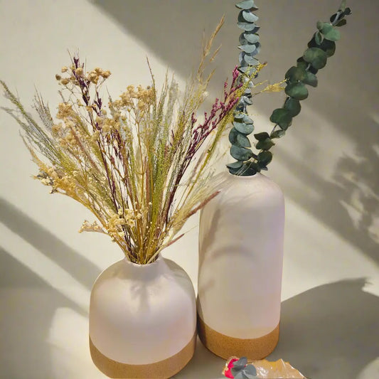 Two white earthbound vases with plant decorations on a light background