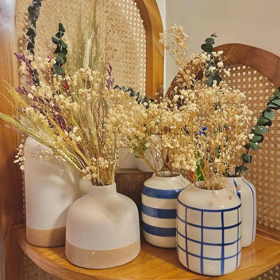 Set of 2 white earthbound decorative vases with dried plants on a wooden shelf