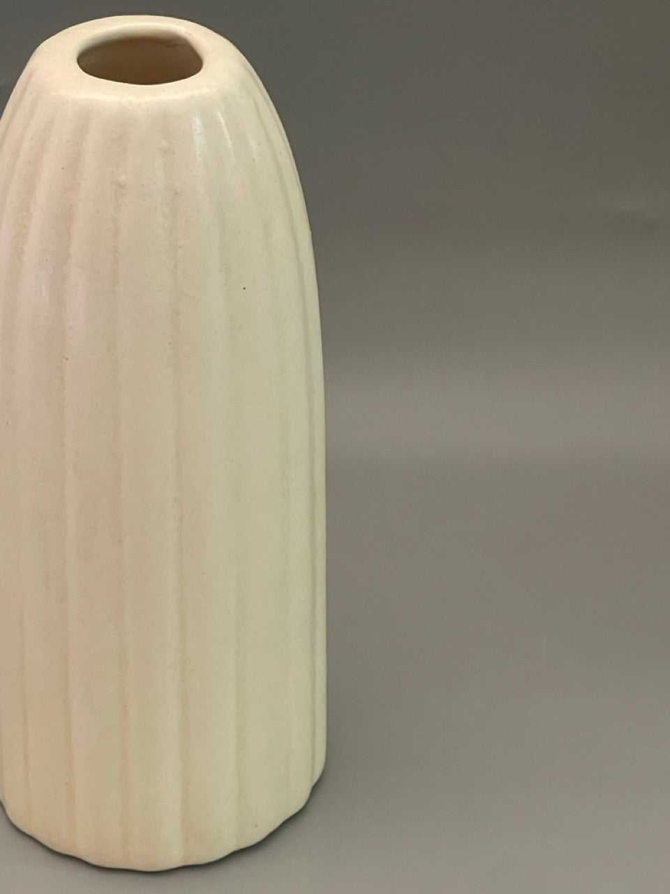 Closeup of Glossy white ceramic vase with ribbed texture, tall 