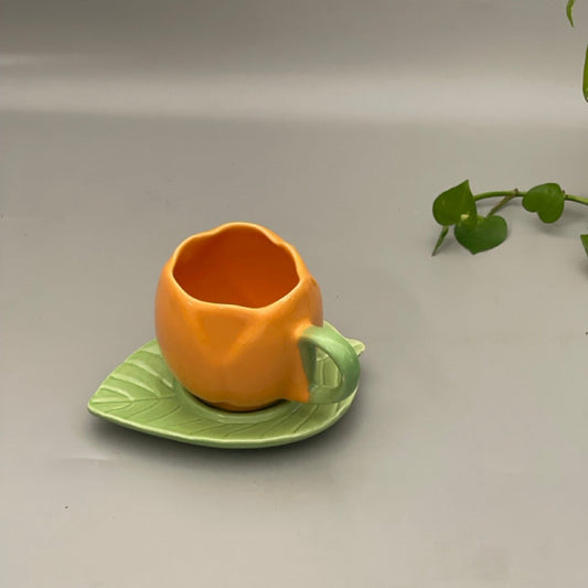 Ceramic cup shaped like a lotus with matching leaf-shaped saucer in glossy red, yellow, and green variants